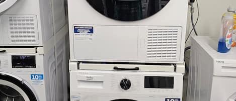 A stack of white washing machines with a digital display, a control panel, and a water tank.