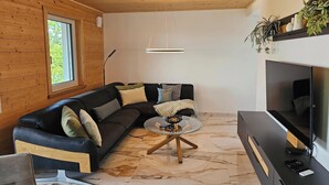 A modern living room with a black leather sofa, a glass coffee table, a flat-screen TV, and wooden flooring. - Premium Apartment City View 8 with XXL Balcony (Pfullendorf)