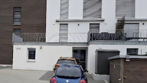 A modern building with a garage, a parked car, and a gated entrance. - Premium Apartment City View 8 with XXL Balcony (Pfullendorf)