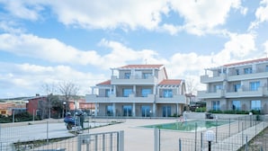 Un edifici d'apartaments modern amb piscina i pati tancat per una tanca.