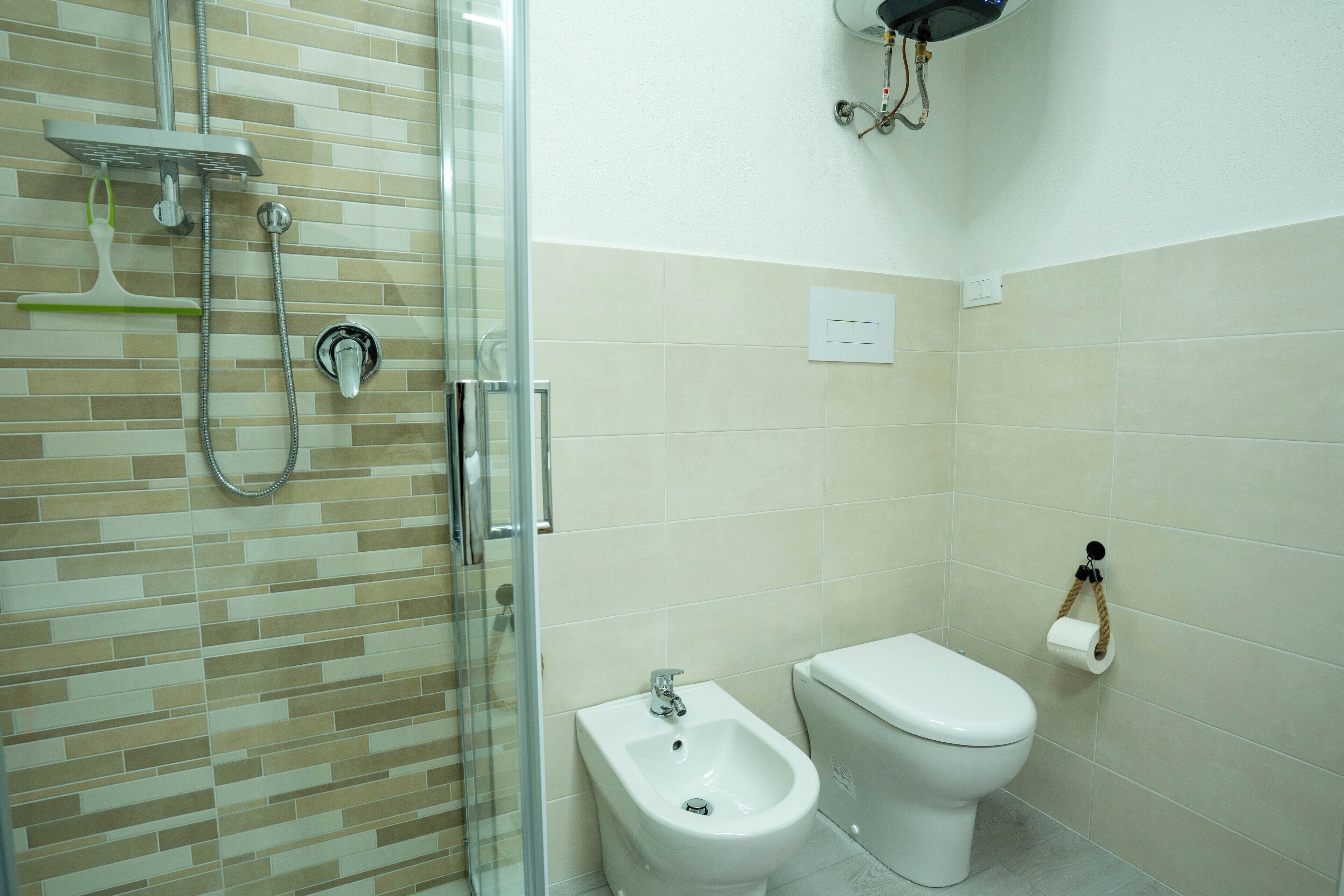 Une salle de bain avec une douche à parois de verre, un bidet et des toilettes.