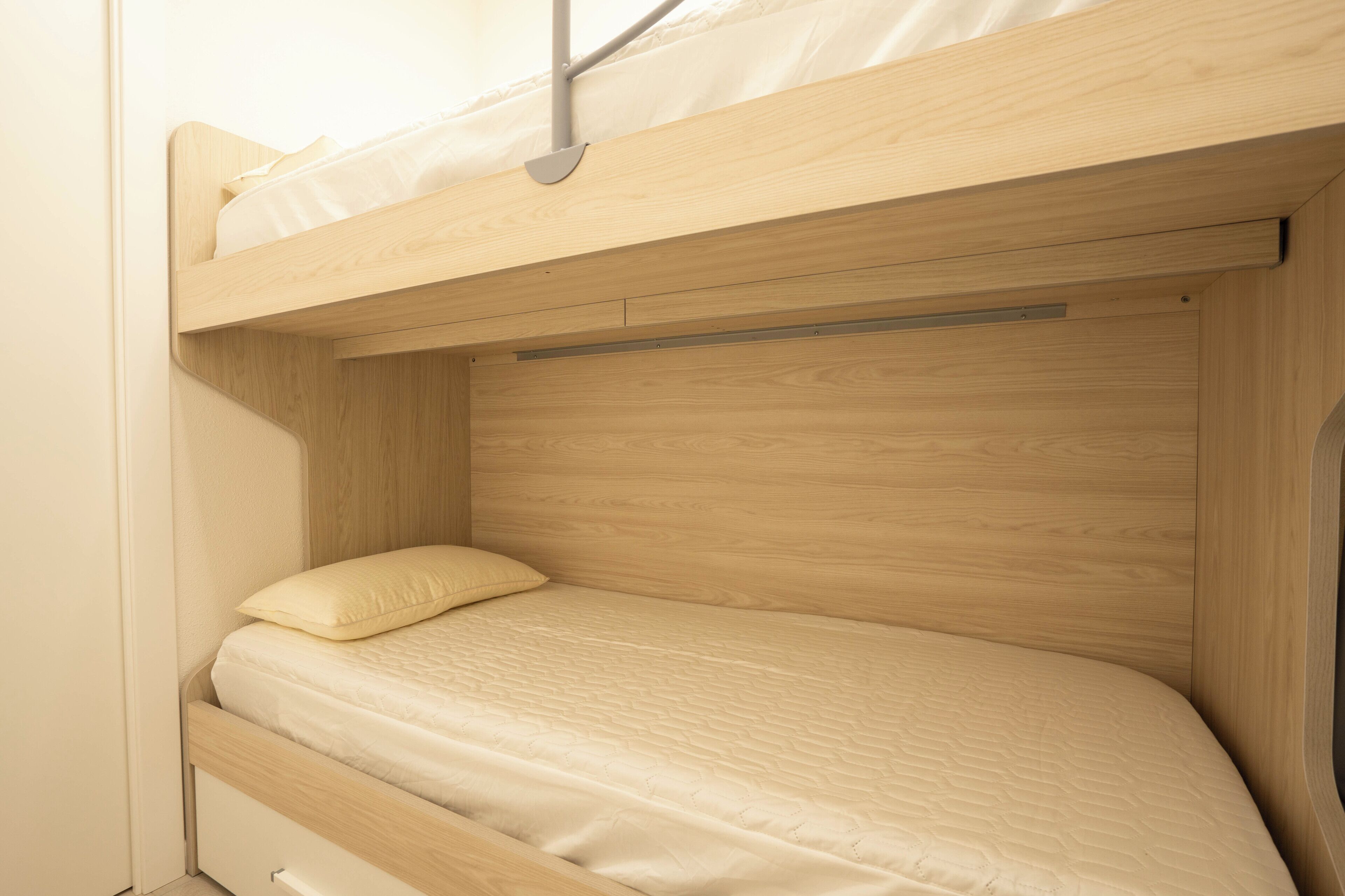 A bunk bed with a wooden frame and a mattress with a quilted cover.