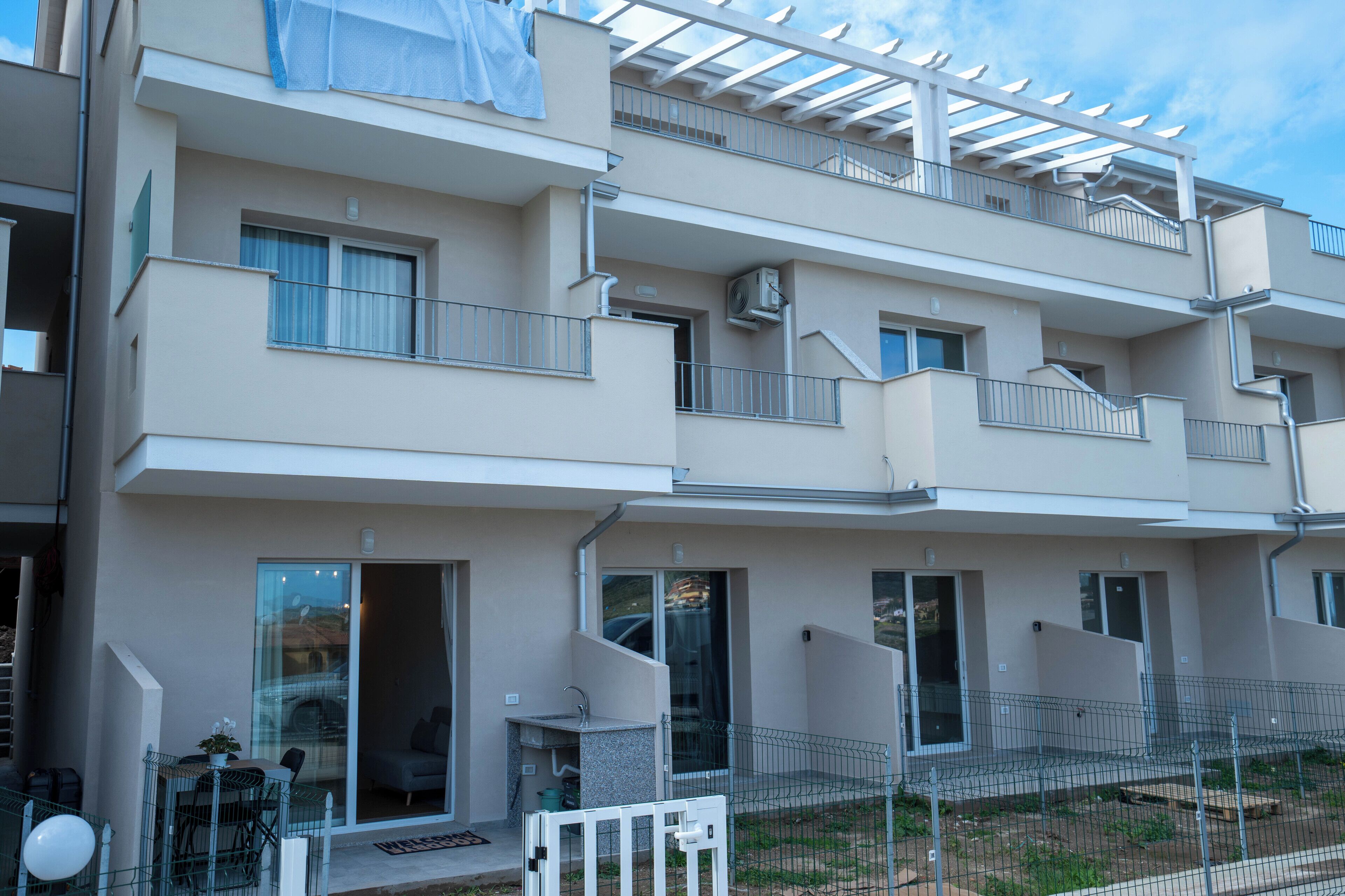 A multi-story residential building with balconies, sliding glass doors, and a fenced outdoor area.