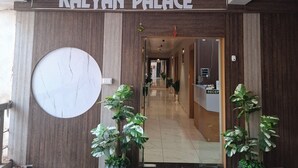 L’entrée de l’hôtel Kalyan Palace, avec un comptoir d’accueil, des plantes en pot et une grande horloge au mur.