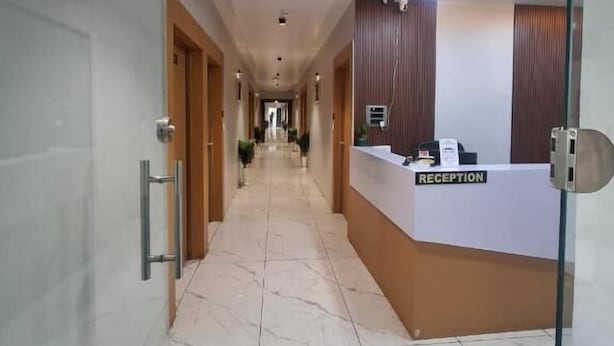 Un hall d’accueil d’hôtel avec un sol en marbre, un comptoir d’accueil et une porte en verre.