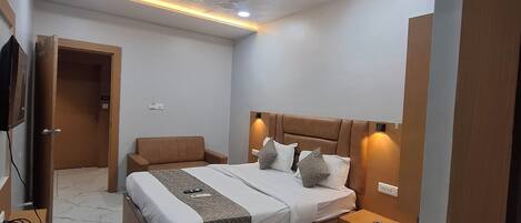 Un dormitorio moderno con una cama, mesitas de noche, un televisor y una puerta.
