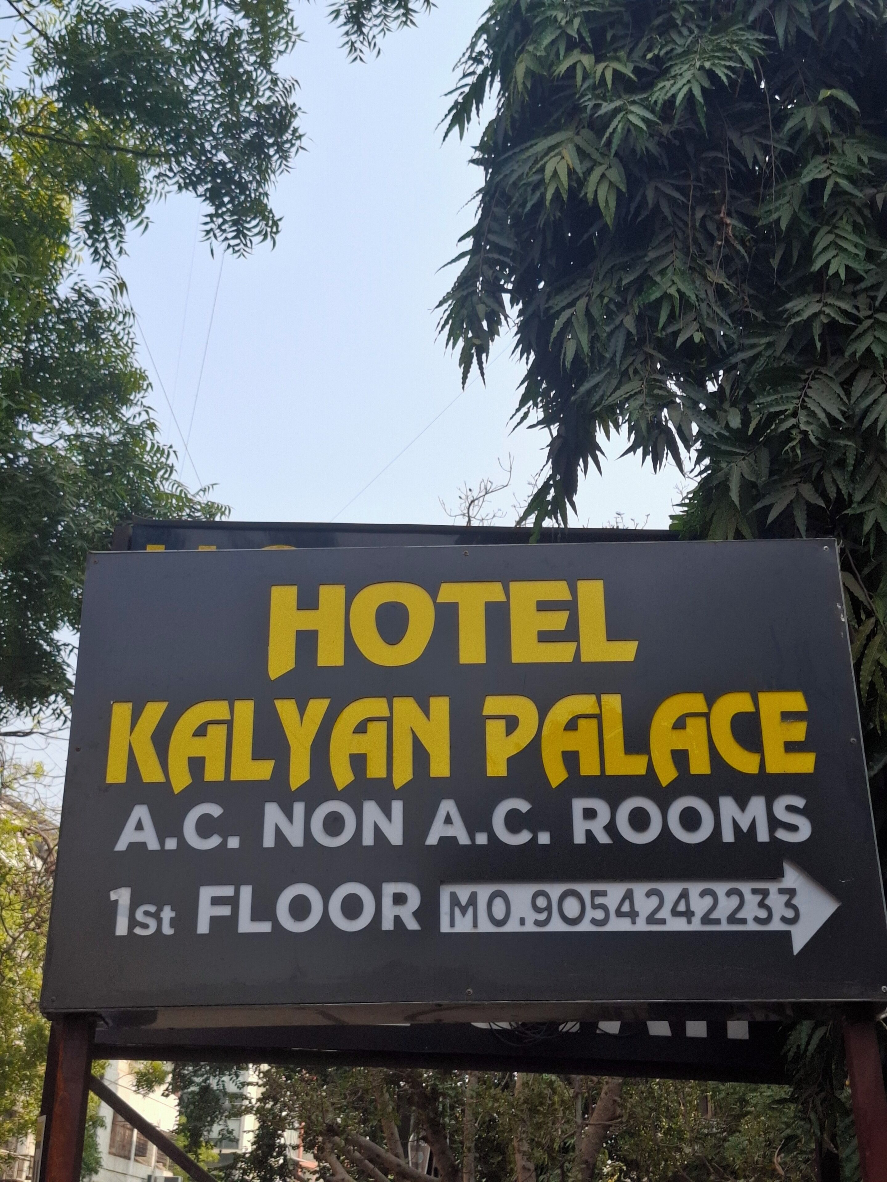 Une enseigne indiquant l’hôtel Kalyan Palace, avec la mention « chambres climatisées » et « chambres non climatisées » au premier étage.
