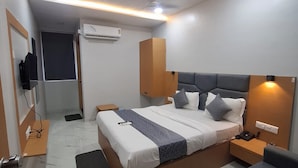 Une chambre d’hôtel moderne avec un lit bien fait, une table de chevet avec un téléphone, un petit bureau et une chaise.