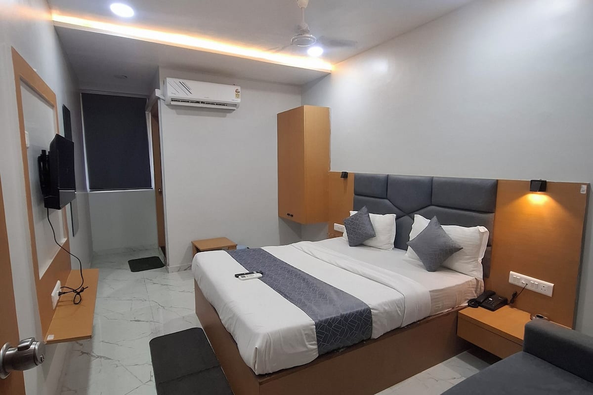 Une chambre d’hôtel moderne avec un lit bien fait, une table de chevet avec un téléphone, un petit bureau et une chaise.