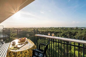 Un balcon avec une table dressée pour le petit-déjeuner, une vue sur un paysage verdoyant et une balustrade.