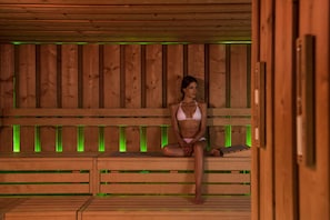 Un sauna en bois, doté de bancs et d’un éclairage vert.