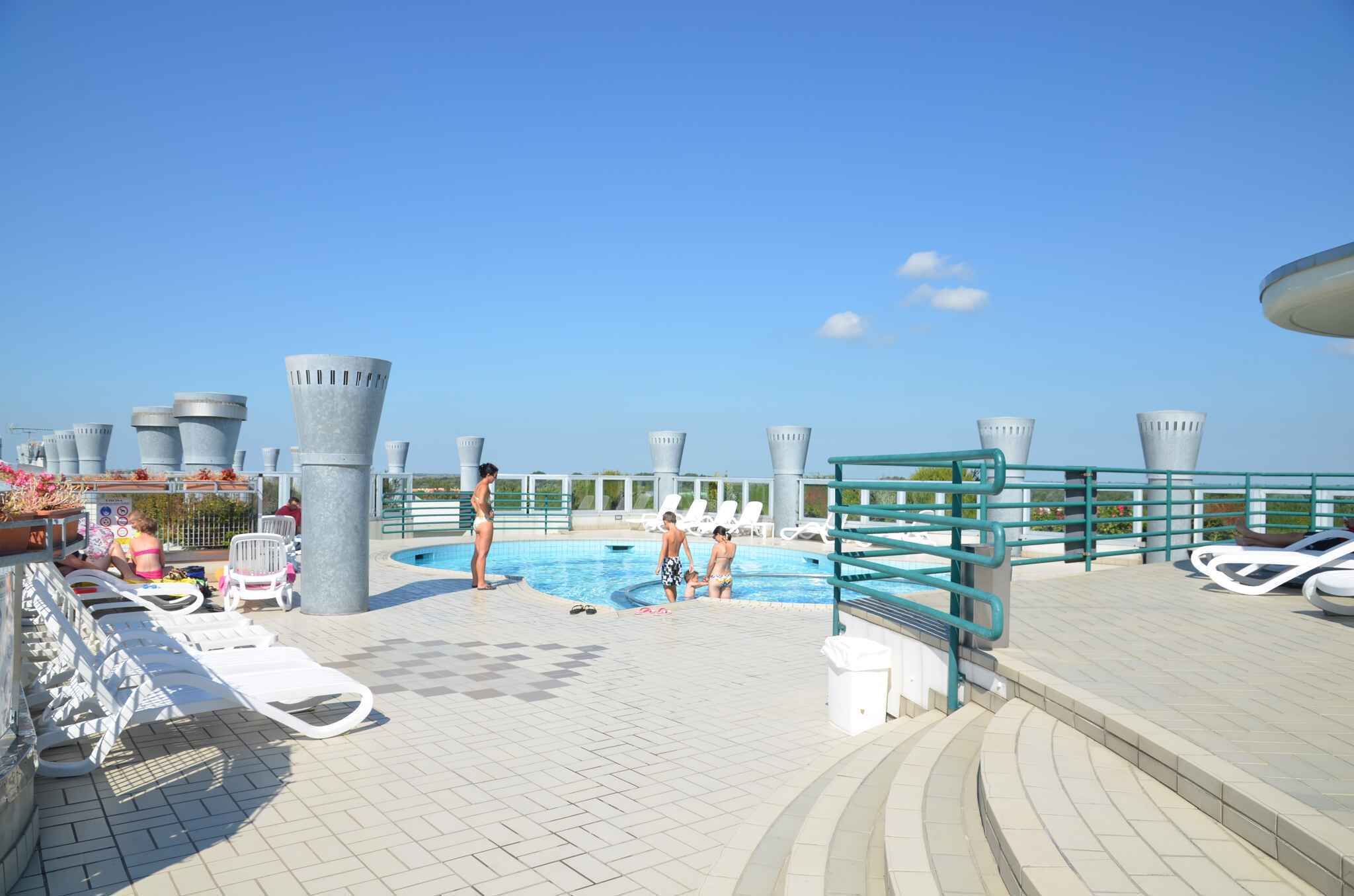 A swimming pool area with lounge chairs, a poolside bar, and a clear blue sky.