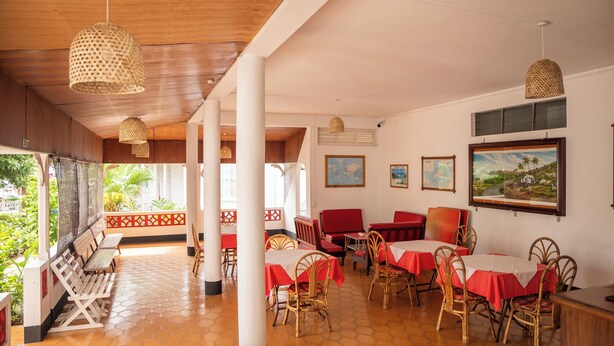 Un restaurante con mesas y sillas rojas al aire libre, y lámparas colgantes de fibra.
