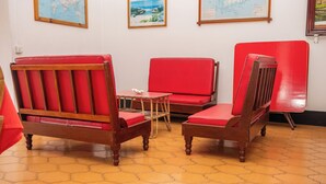 Una habitación con tres sillas tapizadas en rojo y una pequeña mesa de madera.