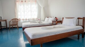 Habitación de hotel con dos camas individuales, una silla de madera, un escritorio y una ventana con cortinas traslúcidas.