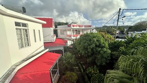 Zona residencial con casas de techos rojos y paredes blancas. Se observan balcones y un pequeño jardín con diversas plantas.