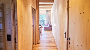Un couloir intérieur en bois mène à un espace de vie comprenant un canapé et une table.