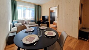 En moderne stue med spiseplads, trævægge, en sofasæt, et fjernsyn og et spisebord dækket til fire personer.