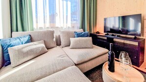 En moderne stue med en modulsofa, et fladskærms-tv og et lille bord med en flaske og glas.