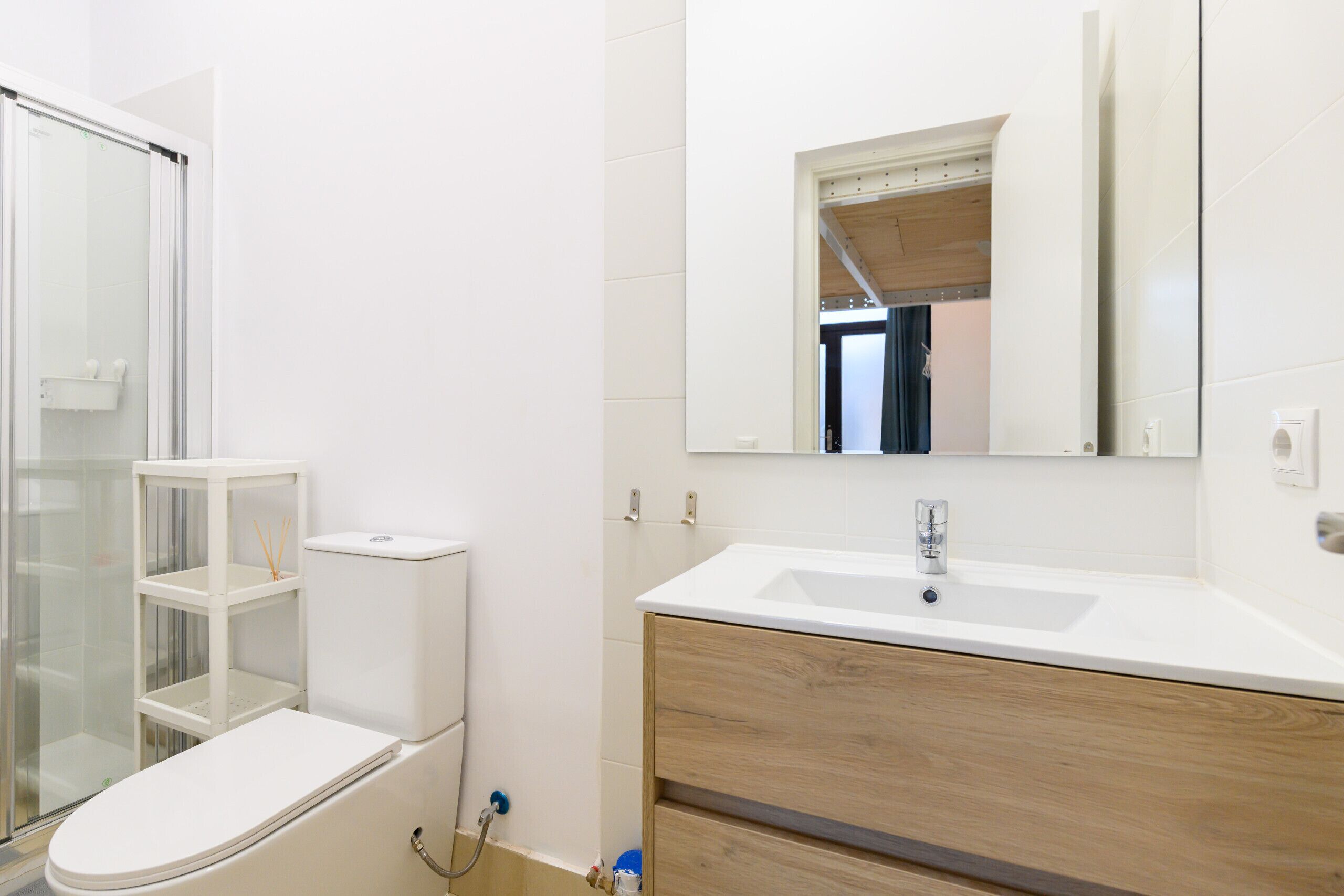 Un baño moderno con inodoro, ducha, tocador y espejo.