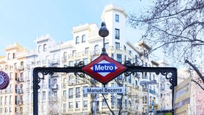 Indicador d'una estació de metro que diu 'Metro Manuel Becerra' amb edificis d'alguns pisos al fons.