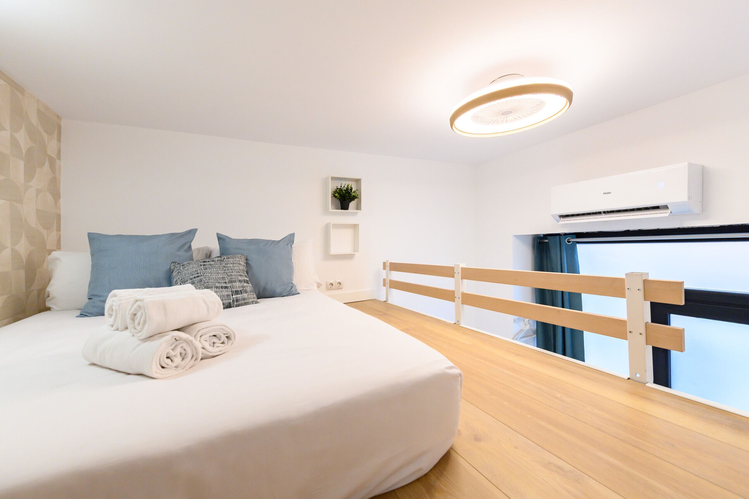 Un dormitorio moderno con una cama bien hecha, un cabecero de madera y un ventanal con vistas.