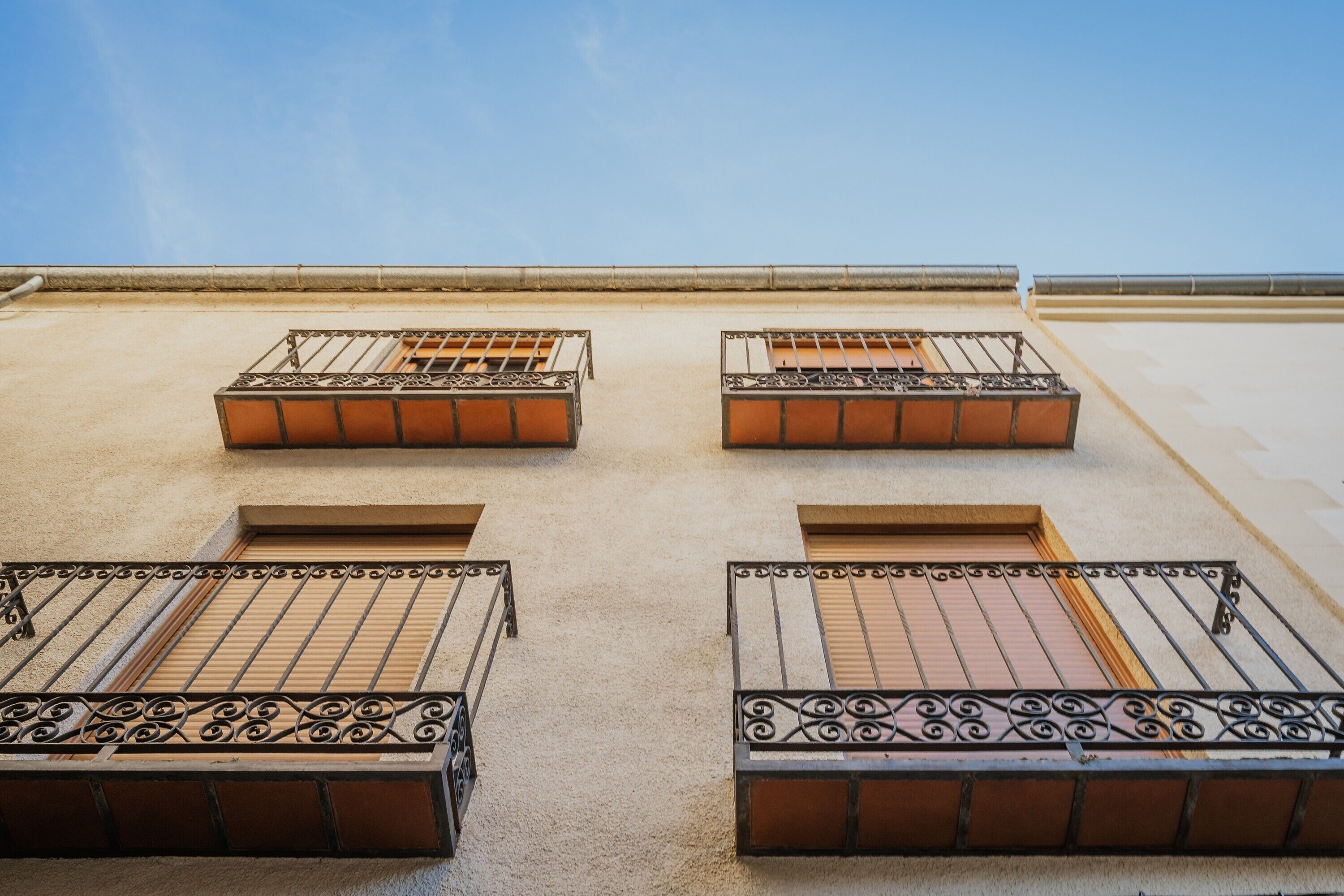Un immeuble doté de quatre balcons, chacun étant muni d’une rambarde en métal et d’une fenêtre.