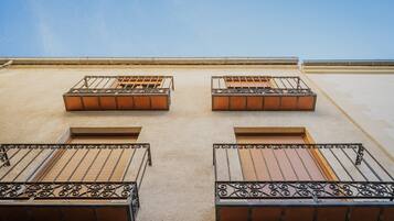 Un immeuble doté de quatre balcons, chacun étant muni d’une rambarde en métal et d’une fenêtre.