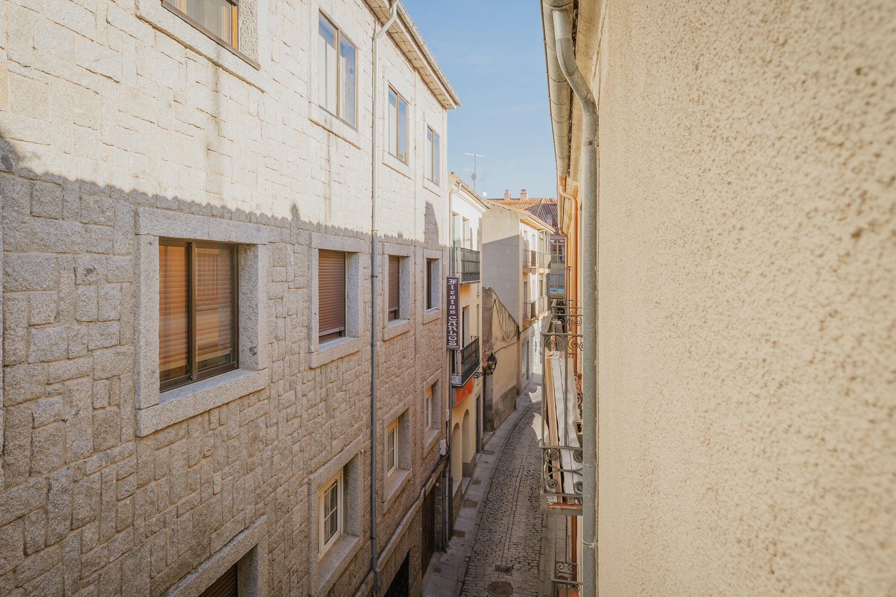 A narrow street with buildings on either side, featuring a cobblestone path and traditional architecture.