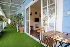 Un espacio al aire libre cubierto con un banco de madera, plantas en macetas y un televisor al fondo.