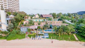 A beachfront property with multiple buildings, including a large hotel with a swimming pool and a smaller house. - Pattaya Paradise Beach Resort (Sattahip)
