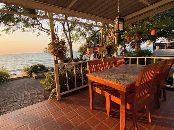 Una mesa y sillas de madera en un patio con baldosas y vista al mar.