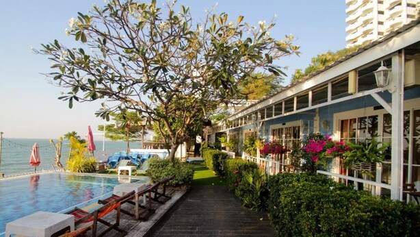 A poolside area with lounge chairs, a pathway, and a view of the sea. - Pattaya Paradise Beach Resort (Sattahip)