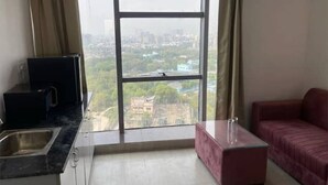 Eine moderne Wohnung mit großem Fenster, Küchenbereich und einem roten Sofa.