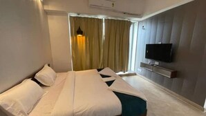 Ein Hotelzimmer mit Bett, Fernseher und einem fenster mit Vorhängen.