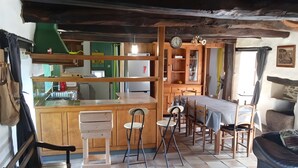 A rustic kitchen with wooden cabinets, a dining table, and a bar area. - TY LOUTI Cottage – Gateway to Huelgoat and Monts d’Arrée (Plouyé)