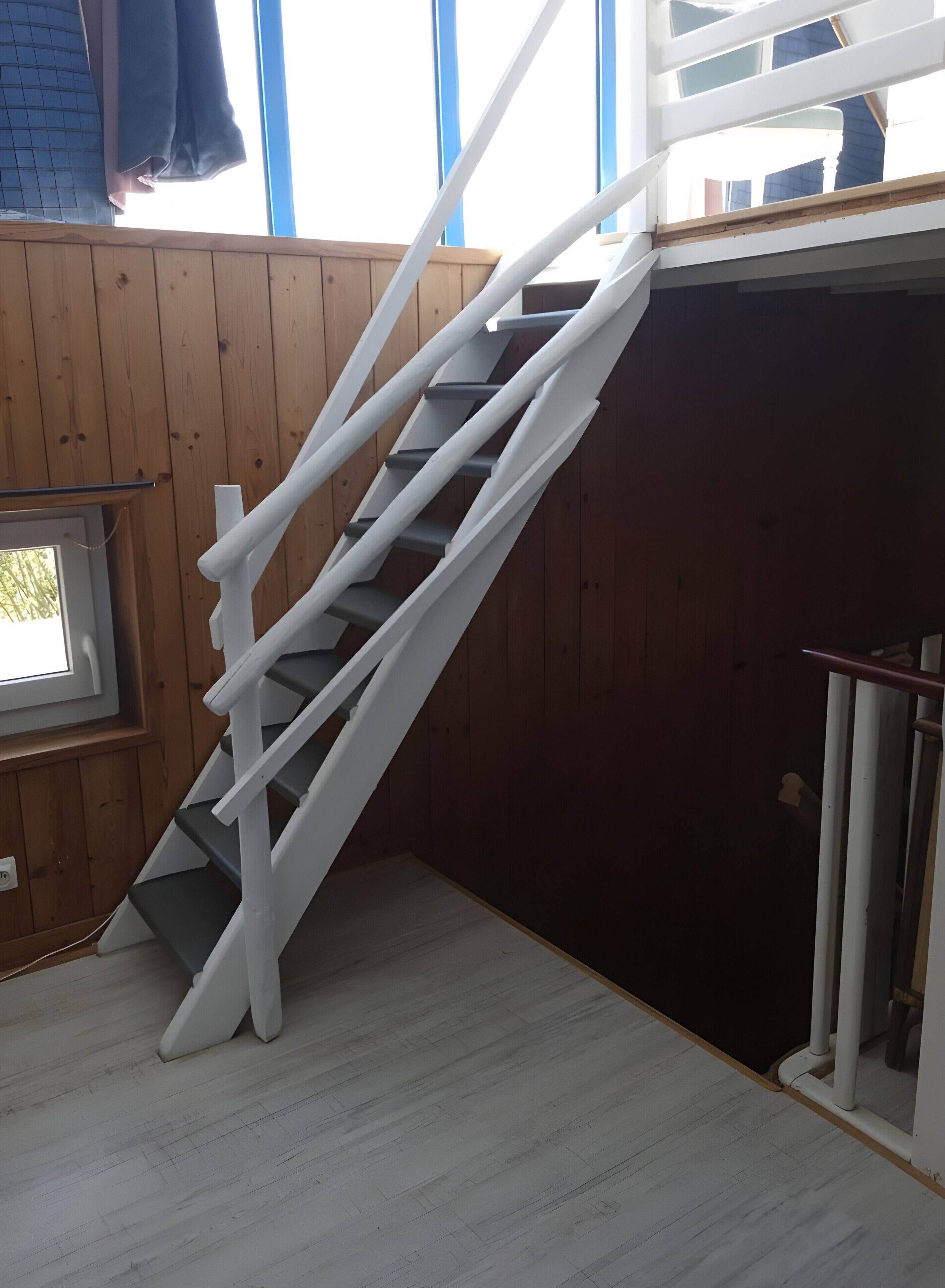 Un interno in legno con una scala bianca che conduce a una stanza buia.