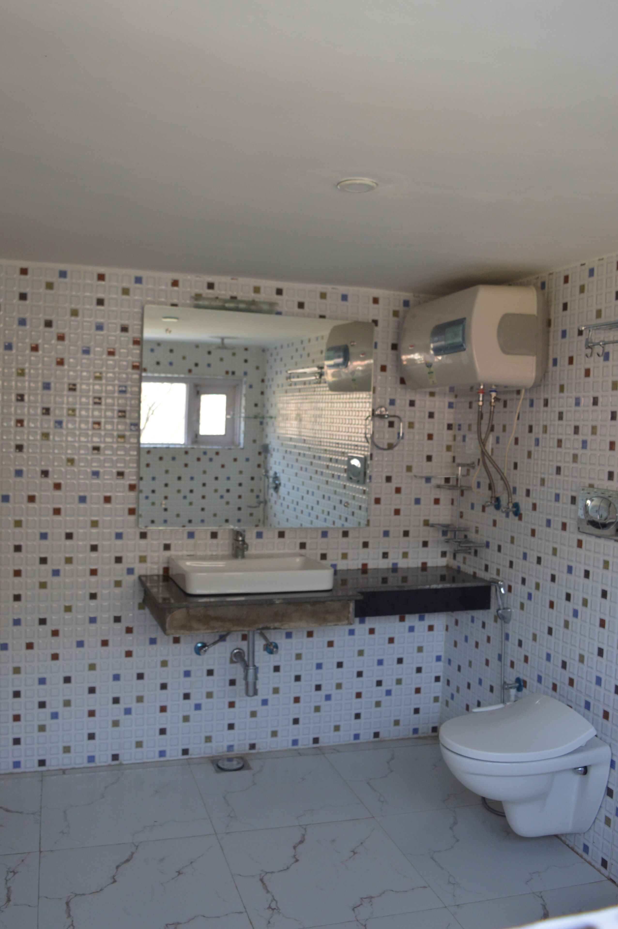 A bathroom with a tiled floor, a sink, a toilet, and a mirror.