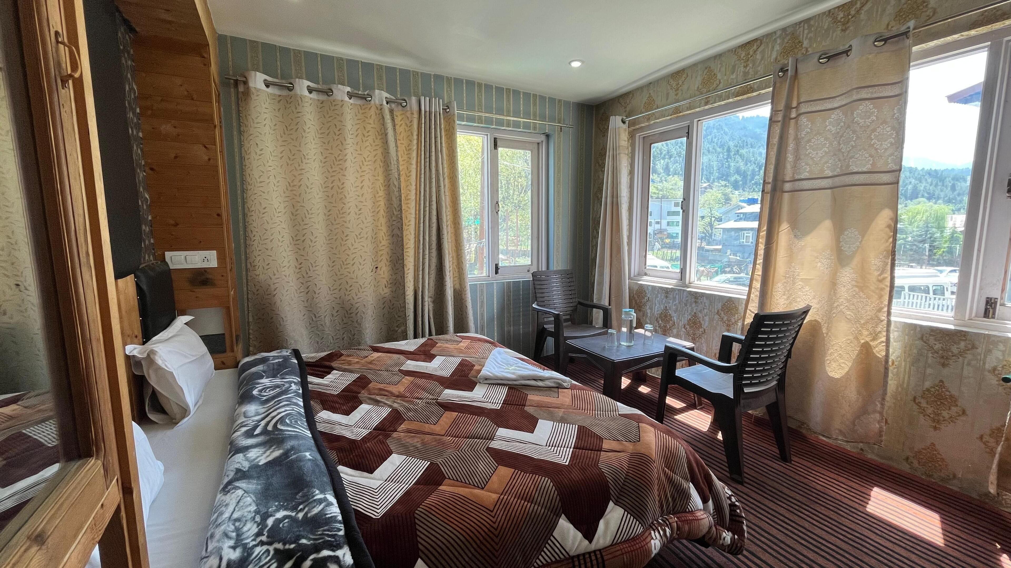 A bedroom with a bed, a desk, and a chair, a window with curtains, and a view of the outside.