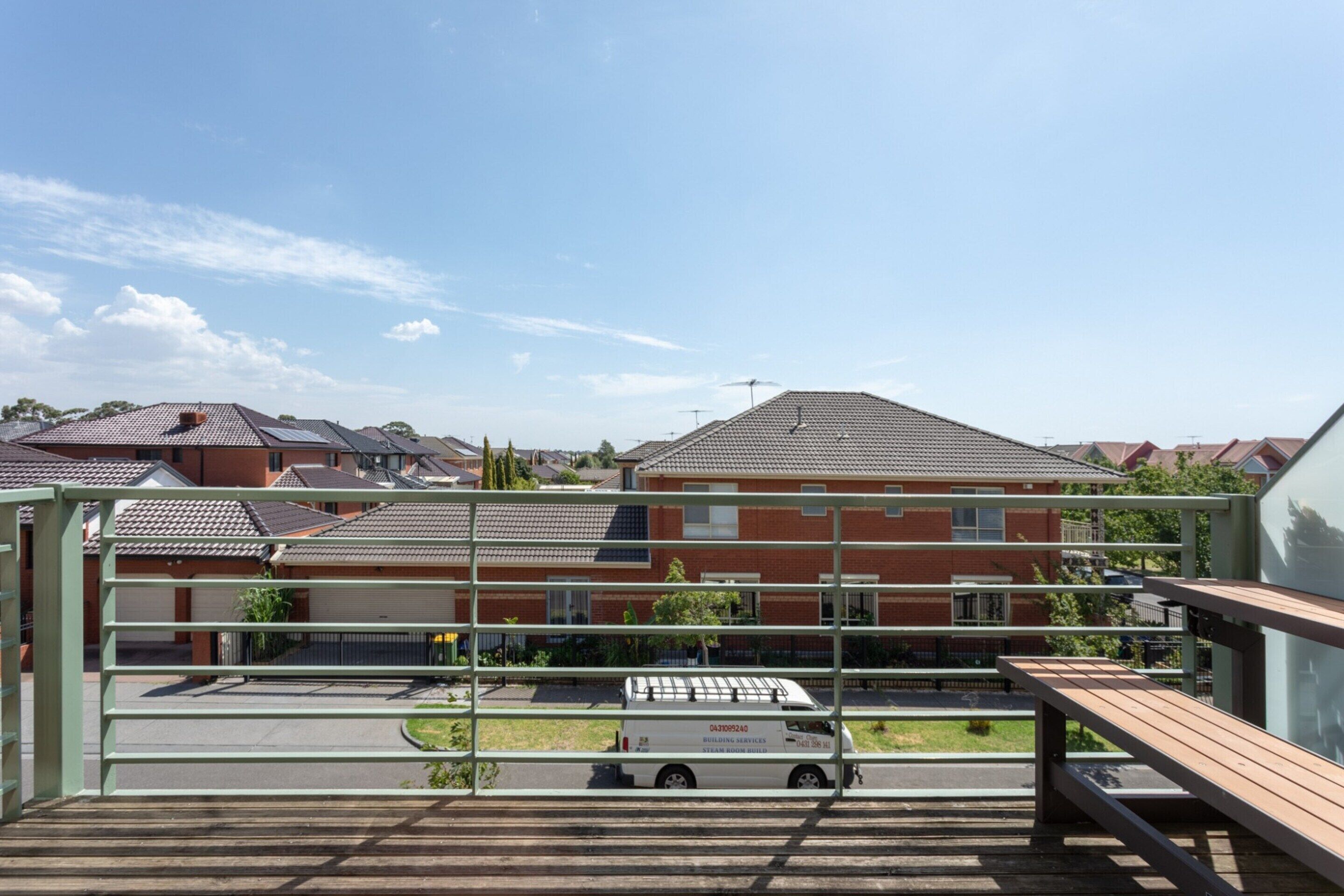 A residential area with a red brick building, a white truck, and a metal fence.