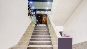 Eine Treppe mit Marmorstufen führt zu einer Empore mit einer Uhr und einem Schild, auf dem "Yash Residency" steht.