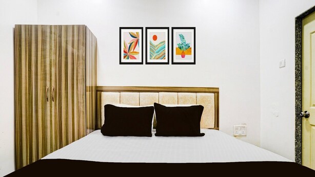 Ein Hotelzimmer mit einem Bett, einem Kleiderschrank und drei gerahmten Kunstwerken an der Wand.