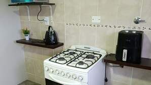 Una cocina con estufa a gas blanca, microondas y cafetera sobre la encimera.