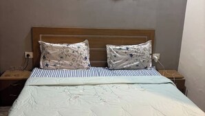 Ein ordentlich bezogenes Bett mit Blumenmuster auf der Bettwäsche und einem hölzernen Kopfteil.