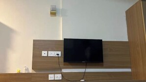 Ein an der Wand befestigter Fernseher mit Holzpaneelen, zwei Steckdosen und einem Stromkabel.