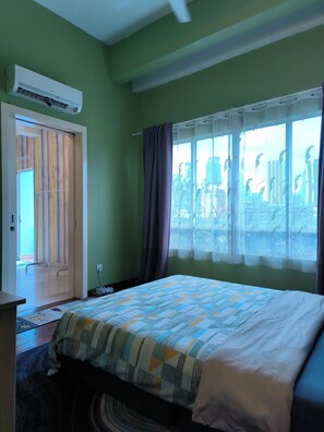 Une chambre d’hôtel avec un lit, une fenêtre avec des rideaux, une porte avec des rideaux à rayures et un appareil de climatisation.