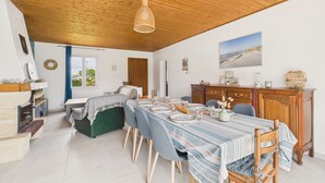 Een eetgedeelte met een houten plafond, een tafel gedekt voor zes personen en een uitzicht op de omgeving door een raam.