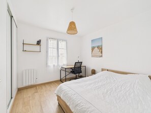 A bedroom with a bed, a desk with a chair, a radiator, a window with curtains, a wall-mounted shelf, and a hanging light fixture. - 800m from beach, lovely house for 6 with garden (Barbâtre)