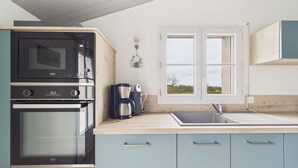 Een kitchenette met een inbouwoven, een koffiezetapparaat en een raam met uitzicht op de omgeving.
