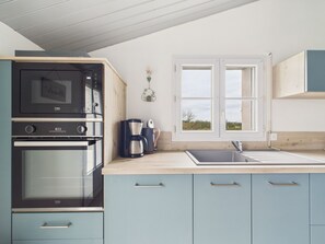 A kitchenette with a built-in oven, a coffee maker, and a window with a view of the outdoors. - 800m from beach, lovely house for 6 with garden (Barbâtre)